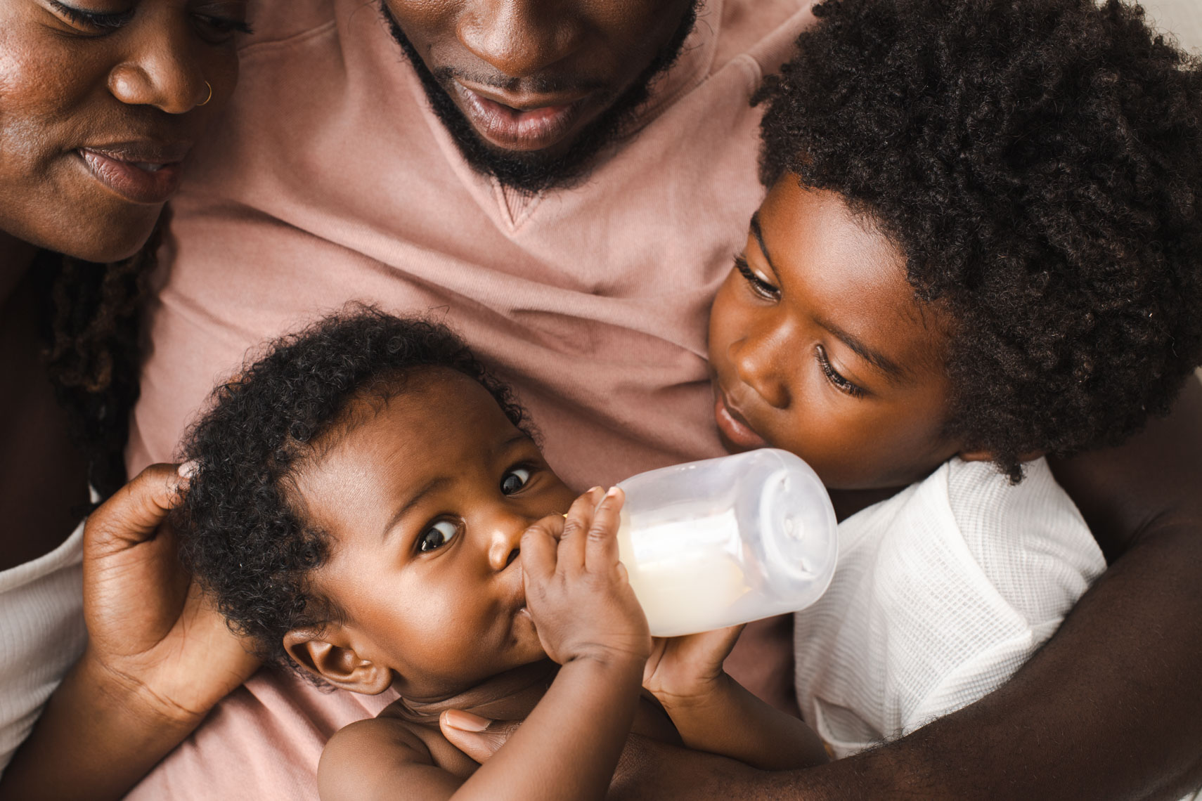 Family with infant drinking out of baby bottle 